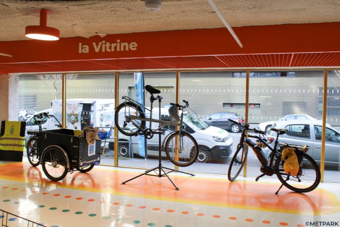 Vue intérieure de la vitrine Metstation avec un vélo cargo, un vélo en réparation et un 3ème vélo en attente sur la droite